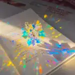 Objet scientifique lumineux en forme d'étoile colorée, projetant des reflets irisés sur une surface blanche. Parfait pour la décoration de science ou comme objet de collection.