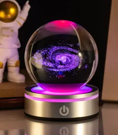 Boule de cristal LED avec vortex cosmique en spirale violette et bleue, éclairée par un socle lumineux rose et doré, décor scientifique et mystique.