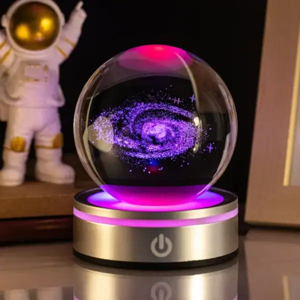 Boule de cristal LED avec vortex cosmique en spirale violette et bleue, éclairée par un socle lumineux rose et doré, décor scientifique et mystique.