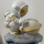 Figurine d'astronaute en tenue blanche avec casque doré, explorant une planète avec une base lunaire, décorée de détails dorés, représentant l'univers et l'exploration spatiale.
