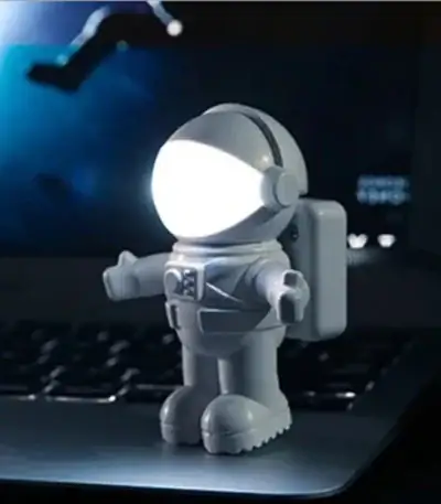 Petite figurine d'astronaute en plastique avec lumière LED intégrée, idéale pour la décoration de bureau ou chambre à thème scientifique, apportant une touche futuriste et ludique.