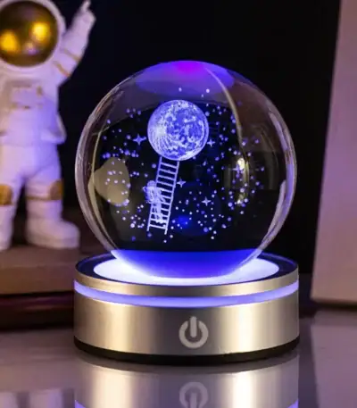 Boule à neige LED avec scène lunaire et astronaute, illuminée en bleu, idéale pour décoration scientifique et éducative.