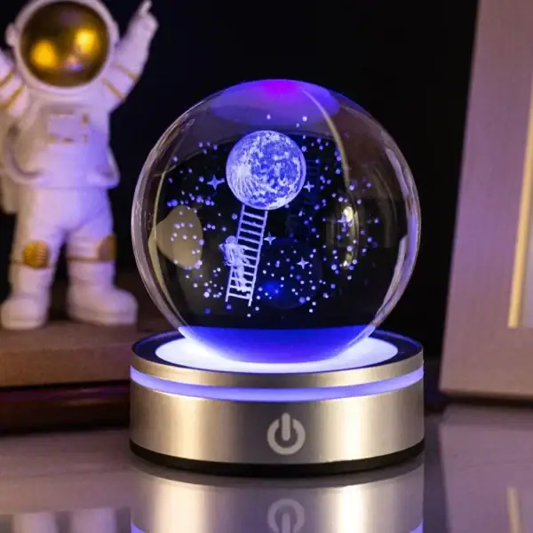 Boule à neige LED avec scène lunaire et astronaute, illuminée en bleu, idéale pour décoration scientifique et éducative.