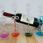 Ensemble de flacons en verre de laboratoire avec tubes à essai colorés, disposés sur une surface en bois, évoquant une décoration scientifique et élégante.