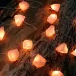 Guirlande lumineuse en pierre de sel rose sur bois brut, ambiance chaleureuse et naturelle.