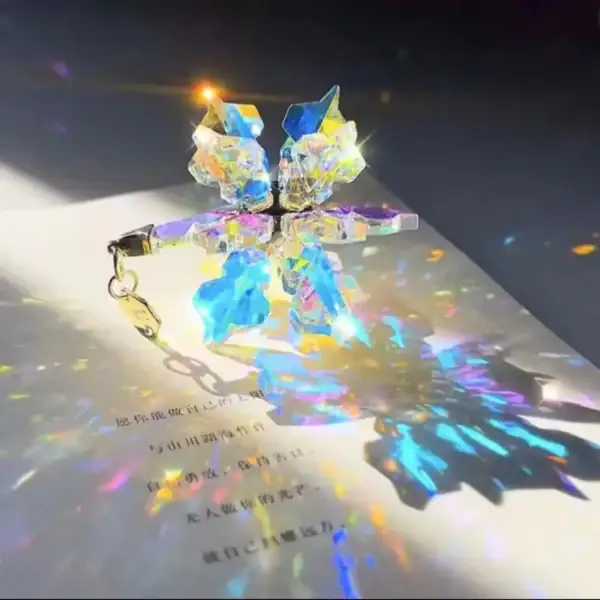 Pendentif en cristal lumineux avec reflets colorés, créant un effet de lumière iridescente et une ombre colorée sur la surface.