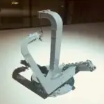 Pince de laboratoire en plastique blanc avec chaîne métallique, utilisée pour manipuler des objets en laboratoire ou pour des activités éducatives scientifiques.