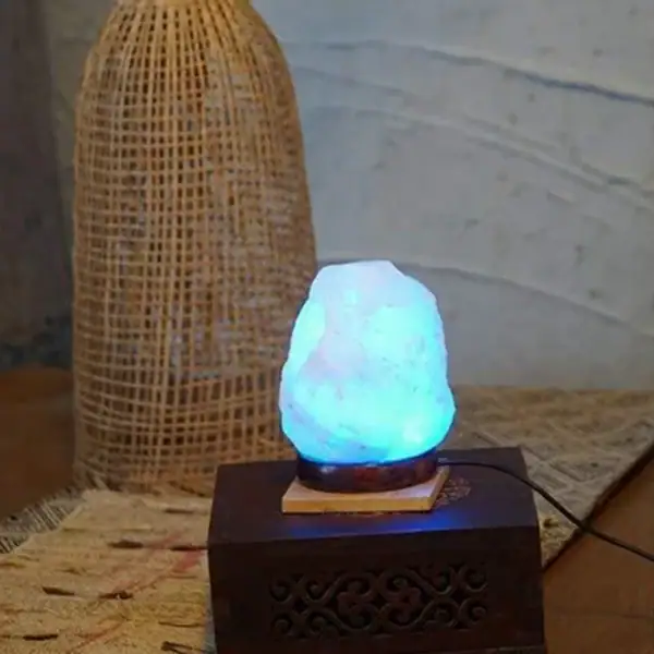 Lampe en cristal de roche illuminée avec une lumière bleue douce, posée sur un socle en bois, décorant un intérieur avec un style naturel et élégant.
