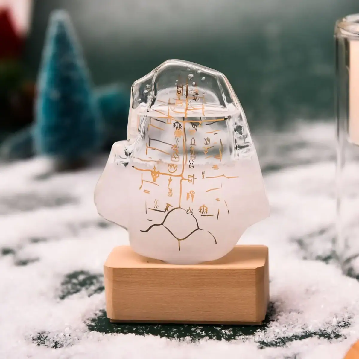 Pendentif en glace transparent avec inscription scientifique gravée, posé sur un socle en bois, dans un décor hivernal avec neige et arbres flous en arrière-plan.