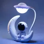 Véhicule spatial décoratif en forme de lune avec un petit astronaute, idéal pour la décoration de chambre ou comme objet de collection sur le thème de l'espace.