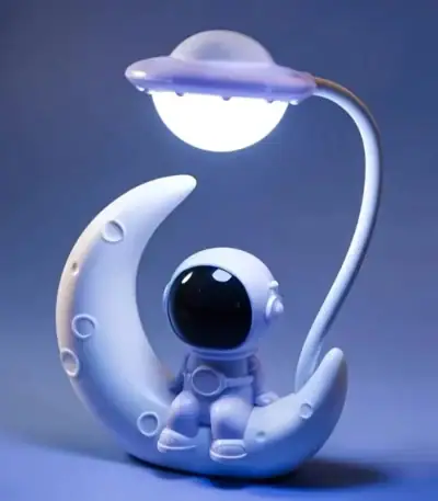 Véhicule spatial décoratif en forme de lune avec un petit astronaute, idéal pour la décoration de chambre ou comme objet de collection sur le thème de l'espace.