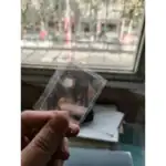 Petit objet scientifique en verre transparent tenu entre les doigts, avec une fenêtre en arrière-plan. Idéal pour décoration ou collection scientifique.