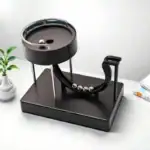 Bille de Newton de bureau avec plateau noir, billes métalliques et rails, décoration scientifique pour bureau ou étagère.