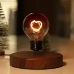 Ampoule décorative avec filament en forme de cœur, éclairage chaud, sur socle en bois naturel.