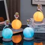 Figurines d'astronautes lumineux sur des sphères colorées, décorations de science-fiction pour bureau ou étagère.