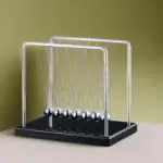 Pétri Newton en métal avec boules suspendues, illustrant la conservation de l'énergie.