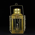 Lanterne à pétrole en laiton vintage avec poignée et chaîne, idéale pour décoration scientifique ou rétro. Parfaite pour un style industriel ou vintage dans un intérieur ou un extérieur.