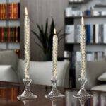 Trois bougies en verre avec flammes allumées sur une table en bois, décor élégant et moderne.