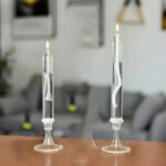 Deux bougies de laboratoire en verre avec spirale intérieure, posées sur une surface en bois, dans un environnement intérieur moderne et épuré.