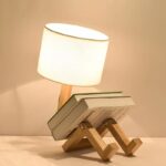 Lampe de lecture créative avec support en forme de personnage assis, idéale pour décorer un bureau ou une chambre avec une touche ludique.