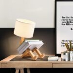Lampe de bureau originale en forme de robot en bois avec abat-jour en tissu, idéale pour une décoration moderne et ludique dans un espace de travail ou une chambre.