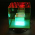 Vitrine en verre avec éclairage LED multicolore, mettant en valeur des objets de décoration ou scientifiques dans une boutique ou un espace d'exposition.