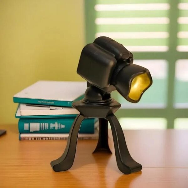 Microscope compact noir avec support stable, idéal pour l'observation scientifique, posé sur un bureau en bois avec livres en arrière-plan dans une pièce lumineuse.