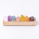 Pierres de cristal multicolores, translucides et brutes, disposées sur un support en bois clair, illustrant la diversité des minéraux pour la décoration ou la collection scientifique.
