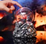 Objet scientifique décoratif avec un socle en forme de crânes et une boule de cristal, idéal pour une décoration originale et mystérieuse.