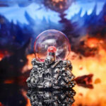 Pendentif décoratif en métal avec des crânes et une boule de cristal, idéal pour la décoration scientifique ou gothique.