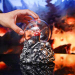 Sculpture en verre représentant un crâne entouré de petits crânes, contenant un liquide rouge mystérieux, idéale pour une décoration originale et sombre.