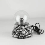 Lampe crâne en métal avec ampoule transparente, décoration originale et macabre pour un intérieur unique.