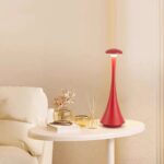 Lampe de décoration scientifique rouge élégante sur une table à côté d'un canapé blanc, ajoutant une touche moderne et originale à votre intérieur.
