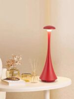Lampe de bureau moderne en forme de champignon rouge avec base élégante, idéale pour la décoration intérieure et l’éclairage d’ambiance dans un espace de travail ou un salon.