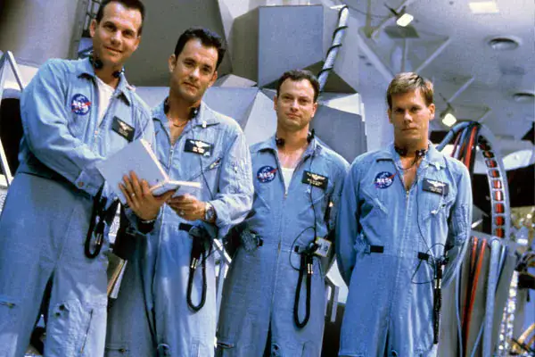 Vier Astronauten in blauen Raumanzügen stehen vor einer Raumkapsel, bereit für eine Weltraummission.