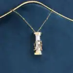 Collier avec pendentif scientifique en cylindre, orné d'une structure métallique dorée, présenté sur un fond bleu foncé.