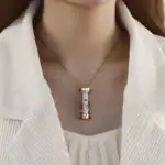 Pendentif scientifique en forme de cylindre doré suspendu à une chaîne fine, porté autour du cou d'une femme. Un bijou élégant inspiré de la science, parfait pour les amateurs de décoration scientifiq.