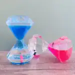 Sablier décoratif avec liquides bleus, roses et transparents, en forme de cristaux, idéal pour la décoration scientifique ou moderne.