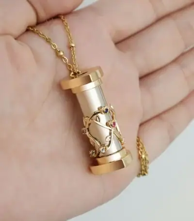 Pendentif scientifique en forme de cylindre avec un motif de branche d'arbre orné de pierres précieuses, suspendu à une chaîne dorée.