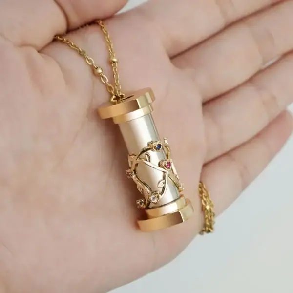 Pendentif scientifique en forme de cylindre avec un motif de branche d'arbre orné de pierres précieuses, suspendu à une chaîne dorée.