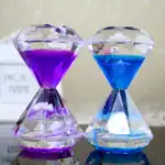 Sablier décoratif en cristal avec liquides colorés violet et bleu, contenant une petite figurine d'oiseau blanc.