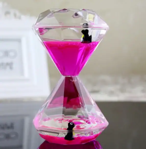Pendentif décoratif en forme de diamant contenant un liquide rose avec deux petits pingouins en plastique à l'intérieur.