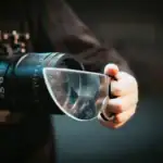 Personne tenant une loupe ou un microscope, mettant en valeur un objet scientifique pour la recherche ou l'observation.