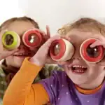 Deux enfants souriants portant des lunettes d'observation colorées, explorant le monde avec curiosité et enthousiasme, dans un contexte éducatif et ludique.