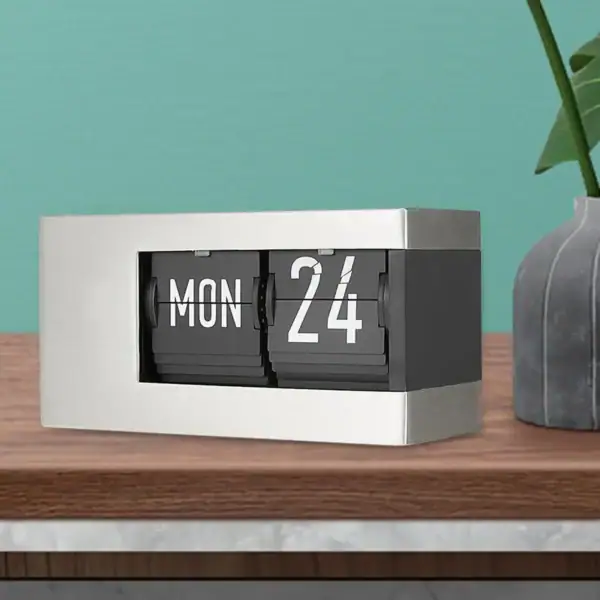Horloge calendrier flip vintage en noir et blanc sur une table en bois, décoratif et pratique pour afficher la date.
