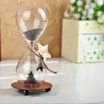 Horloge de sable en verre avec étoile et petit éléphant suspendus.
