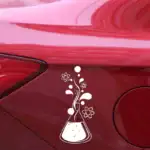 Décoration de voiture avec sticker scientifique représentant un flacon de laboratoire, molécules et symboles atomiques en blanc sur une surface rouge.