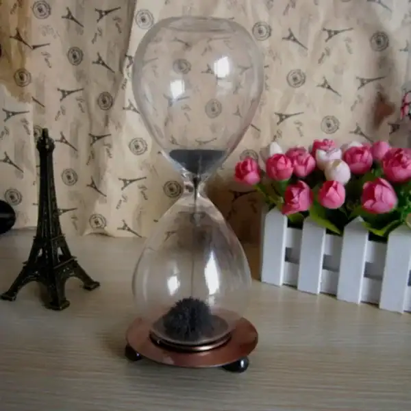Ampoule en verre avec sable noir à l'intérieur, décoration scientifique élégante.