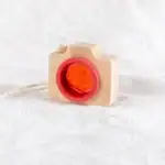 Appareil photo en bois avec un objet orange à l'intérieur, décoratif et éducatif, parfait pour les amateurs de science et de décoration.