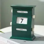 Horloge calendrier en bois vert foncé avec affichage du jour, du mois et de la date, idéal pour la décoration intérieure ou comme objet de bureau original.